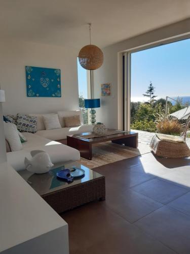 sala de estar con sofá blanco y ventana grande en VILLA ANADINE - Aiguebonne BOULOURIS - PLEINE VUE MER - À 5 minutes à pied de la plage - Climatisée, en Saint-Raphaël