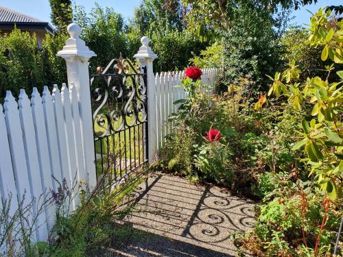 a white fence with a gate in a garden at Dalkeith Boutique Bed & Breakfast in Kaiapoi