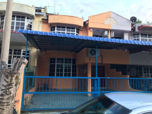 a house with a blue fence and a car parked in front at Suria Permai Homestay in Taiping