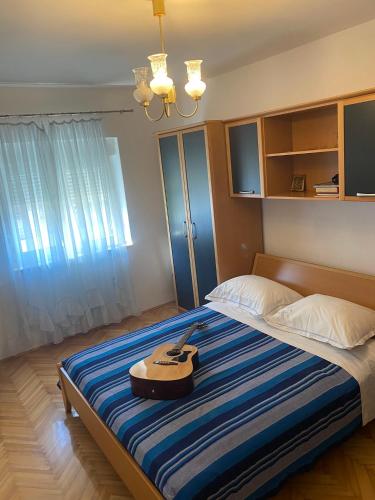a bedroom with a bed with a guitar on it at Apartman Ana Kali in Kali