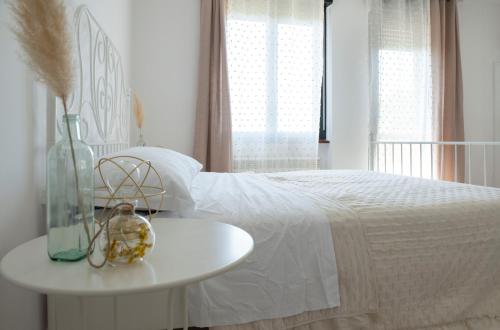 a white bed with a table and a vase on it at Mama Maja in Vacri
