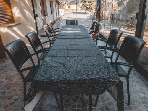 a long black table and chairs on a patio at Mamutfenyő Panzió in Tata