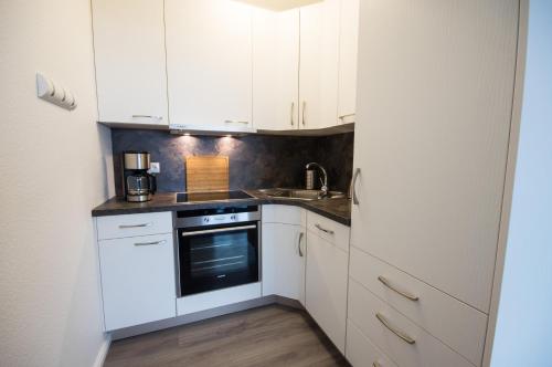 a kitchen with white cabinets and a sink at Am Sahlenburger Strand 04 in Cuxhaven