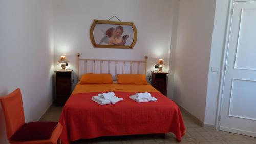1 dormitorio con 1 cama roja y 2 toallas en La casa di Mela, en Leverano