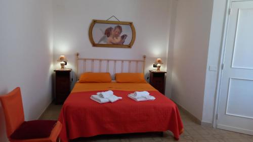 a bedroom with a red bed with two towels on it at La casa di Mela in Leverano