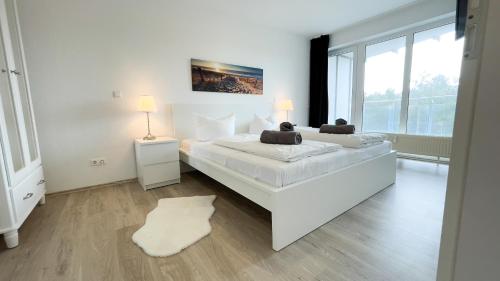 SahlenburgにあるFerienwohnung Nordseebrandung C1.4の白いベッドルーム(大型ベッド1台、大きな窓付)