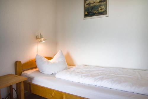 クックスハーフェンにあるStrandnahe Ferienwohnung Frische Brise 04.01のベッド(白いシーツ、ランプ付)