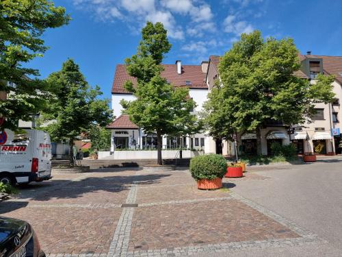 ein weißes Gebäude mit Bäumen auf einem Parkplatz in der Unterkunft Hotel zur Traube in Möglingen