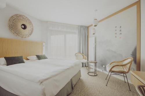 ソポトにあるHotel Zhong Huaの大きなベッドと椅子2脚が備わるホテルルームです。