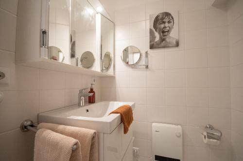 a white bathroom with a sink and a mirror at Marina View in Cuxhaven