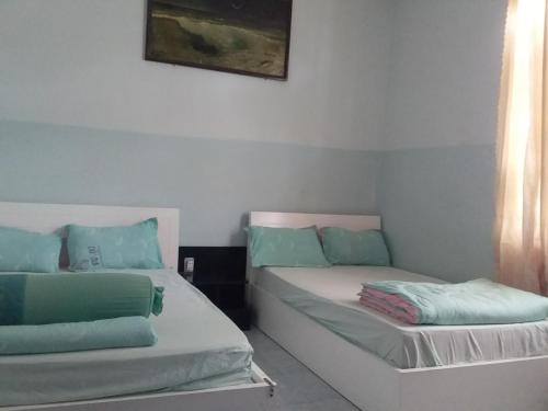 a room with two beds with blue and green pillows at Khách sạn Lê Phan Củ Chi Mới in Cu Chi