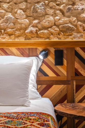 a bed in a room with a stone wall at Vila Origens Boutique Hotel Albufeira – Adults Only in Albufeira