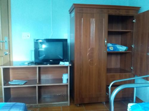 a living room with a tv and a wooden cabinet at Khách sạn Lê Phan Củ Chi Mới in Cu Chi