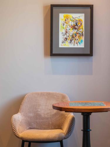 a chair and a table and a picture on the wall at Vila Origens Boutique Hotel Albufeira – Adults Only in Albufeira