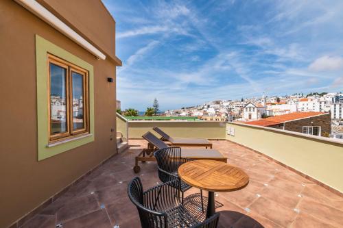 a balcony with tables and chairs and a view of a city at Vila Origens Boutique Hotel Albufeira – Adults Only in Albufeira
