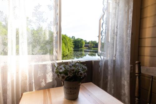 a vase of flowers sitting on a table near a window at Laivu māja Ezerkrasti in Alūksne