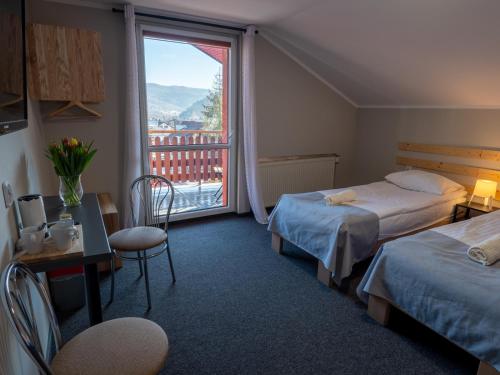 ein Hotelzimmer mit 2 Betten und einem großen Fenster in der Unterkunft Ada in Muszyna