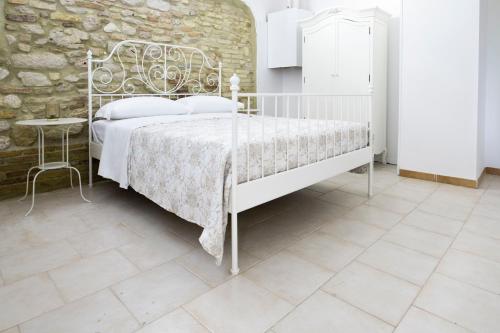 a bedroom with a white bed and a stone wall at Mama Maja in Vacri