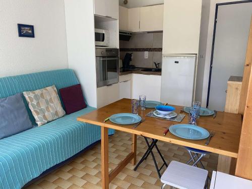 un salon avec une table et un canapé bleu dans l'établissement Studio cabine climatisé, plage à 2 pas, 4 couchages, parking privé - FR-1-250-193, au Grau-du-Roi