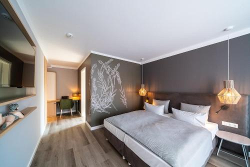 a bedroom with a large bed with a gray wall at Landhotel Rittmeister & Kräuter-SPA Adults Only in Rostock