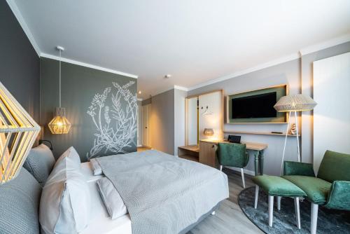 a bedroom with a bed and a desk and a tv at Landhotel Rittmeister & Kräuter-SPA in Rostock