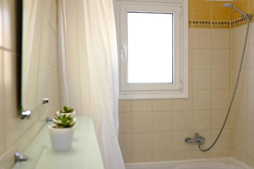a bathroom with a shower and a sink and a window at Villa Boukari in Chlomós
