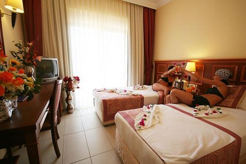 a woman sitting on two beds in a hotel room at HİMEROS BEACH HOTEL in Kemer