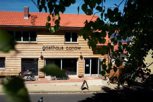 a wooden building with a sign in front of it at Gasthaus Canow in Wustrow