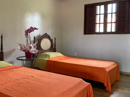 um quarto com duas camas com lençóis laranja e uma janela em Estância EK em Franca