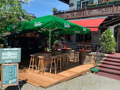 a cafe with a green umbrella and tables and stools at Serviced Apartments VILLA LICHT in Kitzbühel