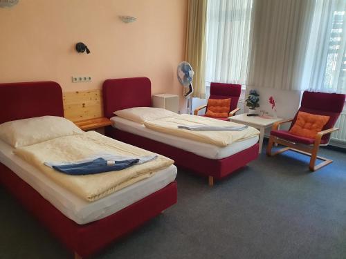 a room with three beds and two chairs and a table at Pension zum Lichtenberger in Berlin