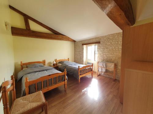 une chambre avec deux lits et une fenêtre dans l'établissement Le Vieux Monastere, à Saint-Hilaire-de-Villefranche