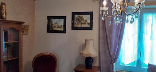 Una habitación con una lámpara de araña y una mesa con una lámpara y una ventana en propriété familiale MERLE proche PARAY LE MONIAL en Vauban