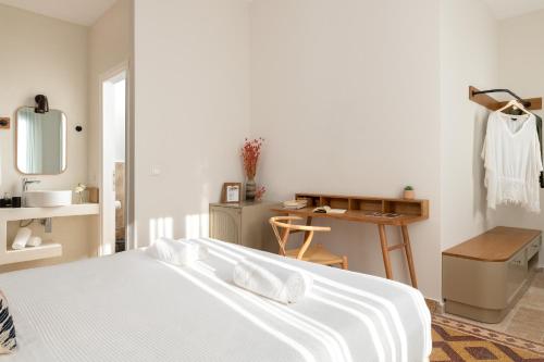 a white bedroom with a bed and a desk at Casa Natura in Rhodes Town
