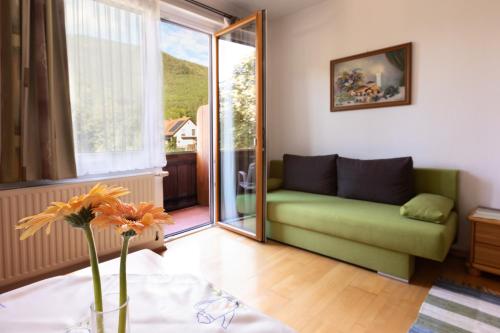 a living room with a green couch and a window at Frühstückspension Rottensteiner in Otterthal