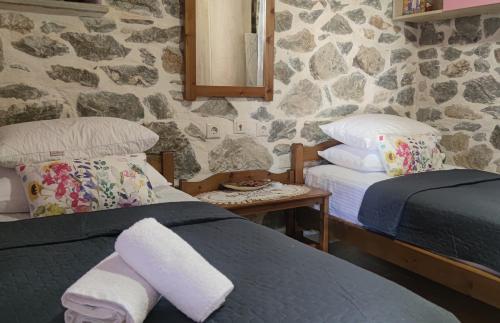 a bedroom with two beds and a stone wall at Marios guesthouse Pelion in Tsagarada