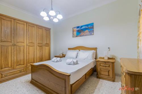 1 dormitorio con 1 cama con sábanas blancas y armarios de madera en Seafront 2 Bedroom Apartment overlooking Bay, en Is-Sellum