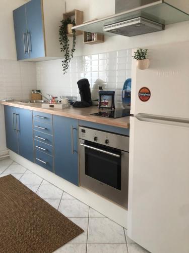 La cuisine est équipée de placards bleus et d'un réfrigérateur blanc. dans l'établissement Jeter l’ancre - studio, à Calais