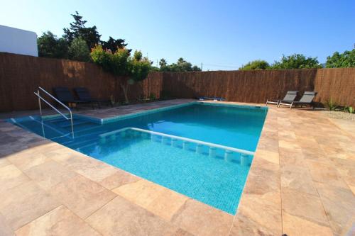 a swimming pool in a backyard with a wooden fence at Ishel Trafalgar in Zahora