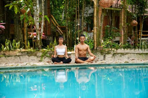 a man and woman sitting in meditation near a swimming pool at Valley Village Phu Quoc in Phu Quoc