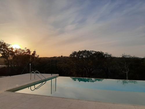 a swimming pool with the sunset in the background at Monte Vale Manhãs by Hi Alentejo in São Bartolomeu da Serra