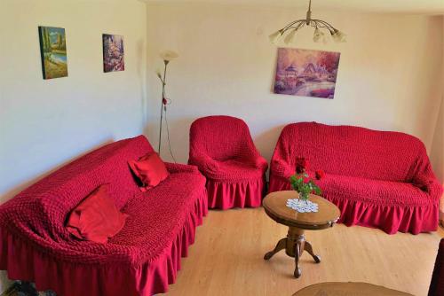 a living room with two red chairs and a table at Home in Banja Luka- Vikendica za iznajmljivanje in Banja Luka