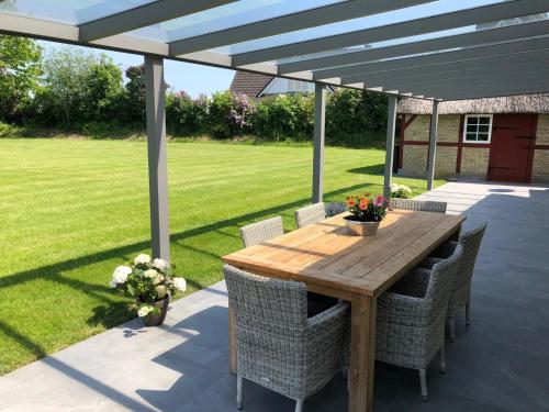 einen Holztisch und Stühle unter einer Pergola in der Unterkunft Reethaus Gaarwang in Gelting