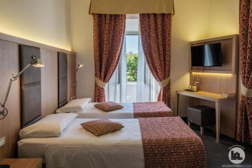 a hotel room with two beds and a window at Hotel Casa Valdese Roma in Rome