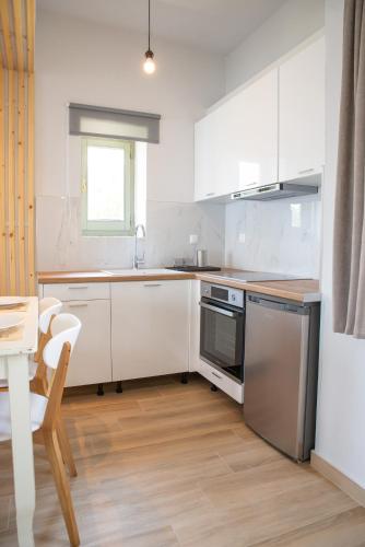a kitchen with white cabinets and a table and a dining room at Marabou Hotel Chorefto in Chorefto