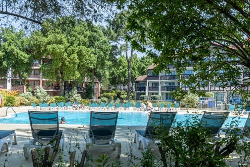 - une piscine avec des chaises bleues et des personnes dans un complexe dans l'établissement Le Gouic Joli Appartement Piscine, à Moliets-et-Maa