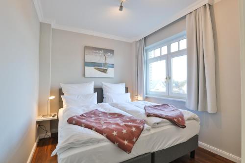 ein Schlafzimmer mit einem großen Bett mit Fenster in der Unterkunft Sylt Beach in Wenningstedt-Braderup