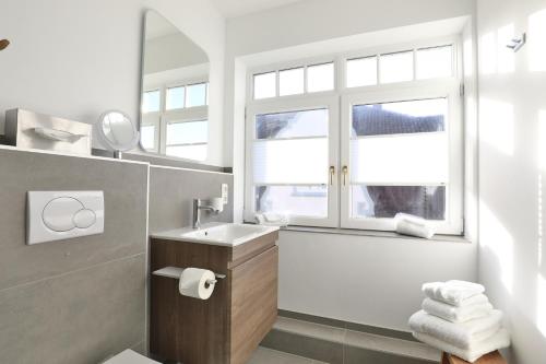 ein weißes Badezimmer mit Waschbecken und Spiegel in der Unterkunft Sylt Beach in Wenningstedt-Braderup