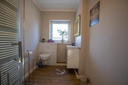 a small bathroom with a toilet and a window at Sylt Like in Tinnum