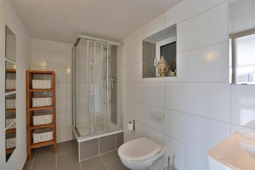 La salle de bains blanche est pourvue d'une douche et de toilettes. dans l'établissement Strandhaus, à Hörnum